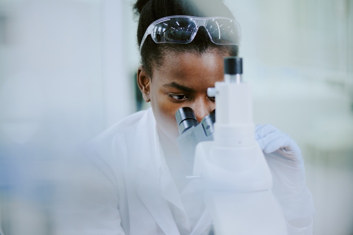 Female scientist examining samples through advanced microscope in laboratory