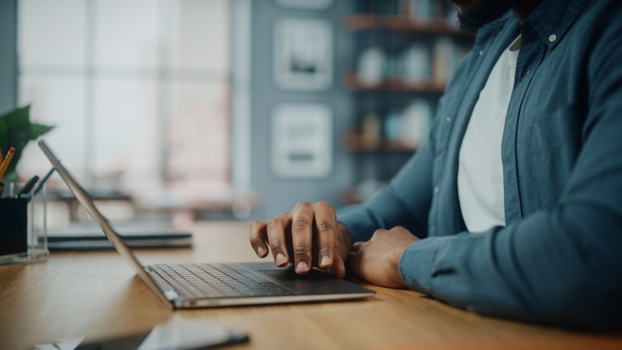 close up of hands on black man working on laptop