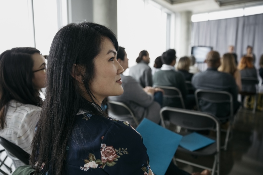 Confident, ambitious businesswoman listening in conference audience