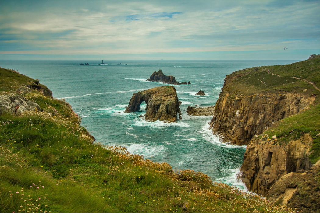 a grassy cliff by a clear ocean scape